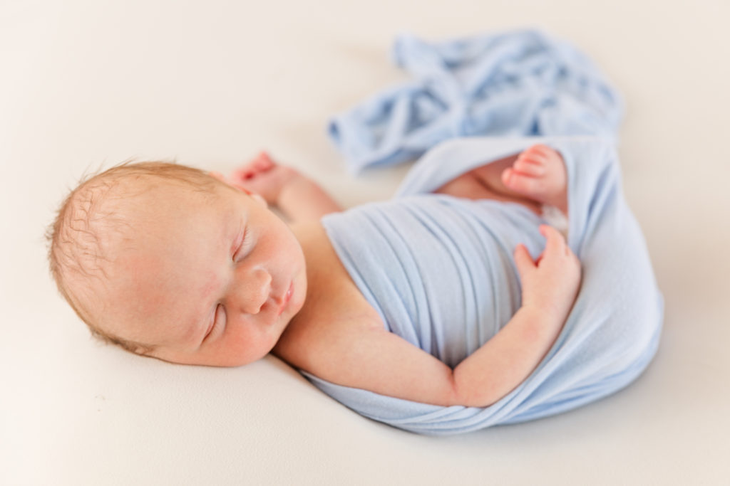 newborn baby in blue swaddle sleeping peacefully