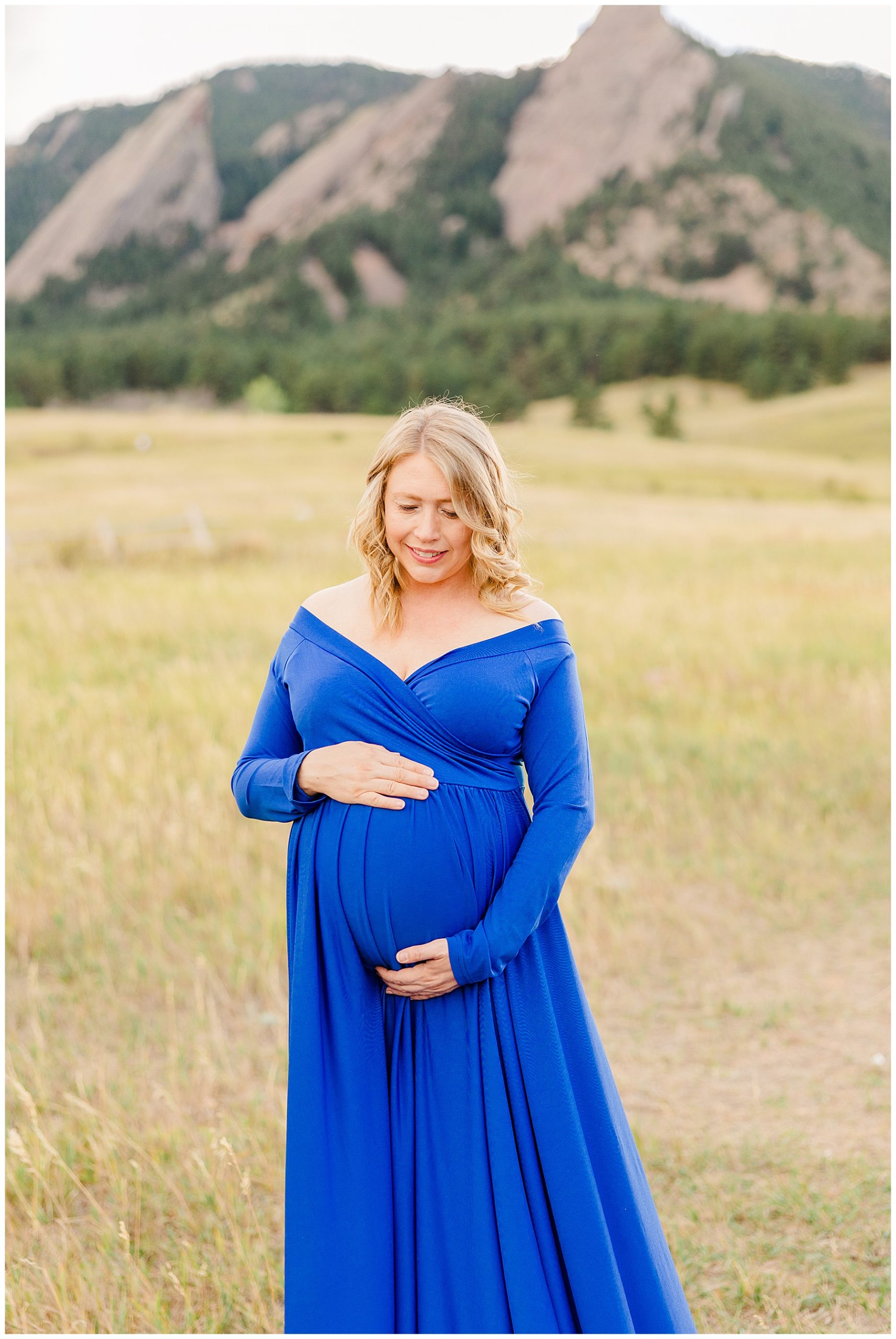 mom looks down at her baby bump during maternity session