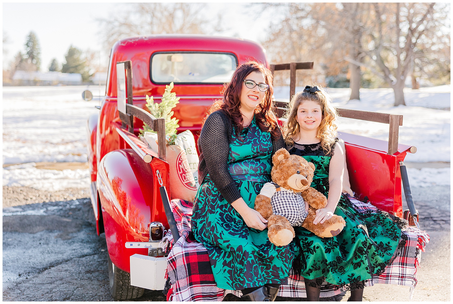 mother and daughter sit together with teddy bear in green matching dresses