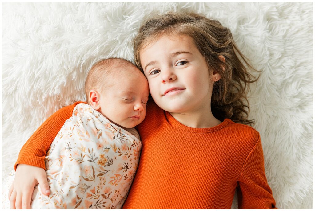 Girl poses with her newborn sister for light and airy photos in Northern Colorado