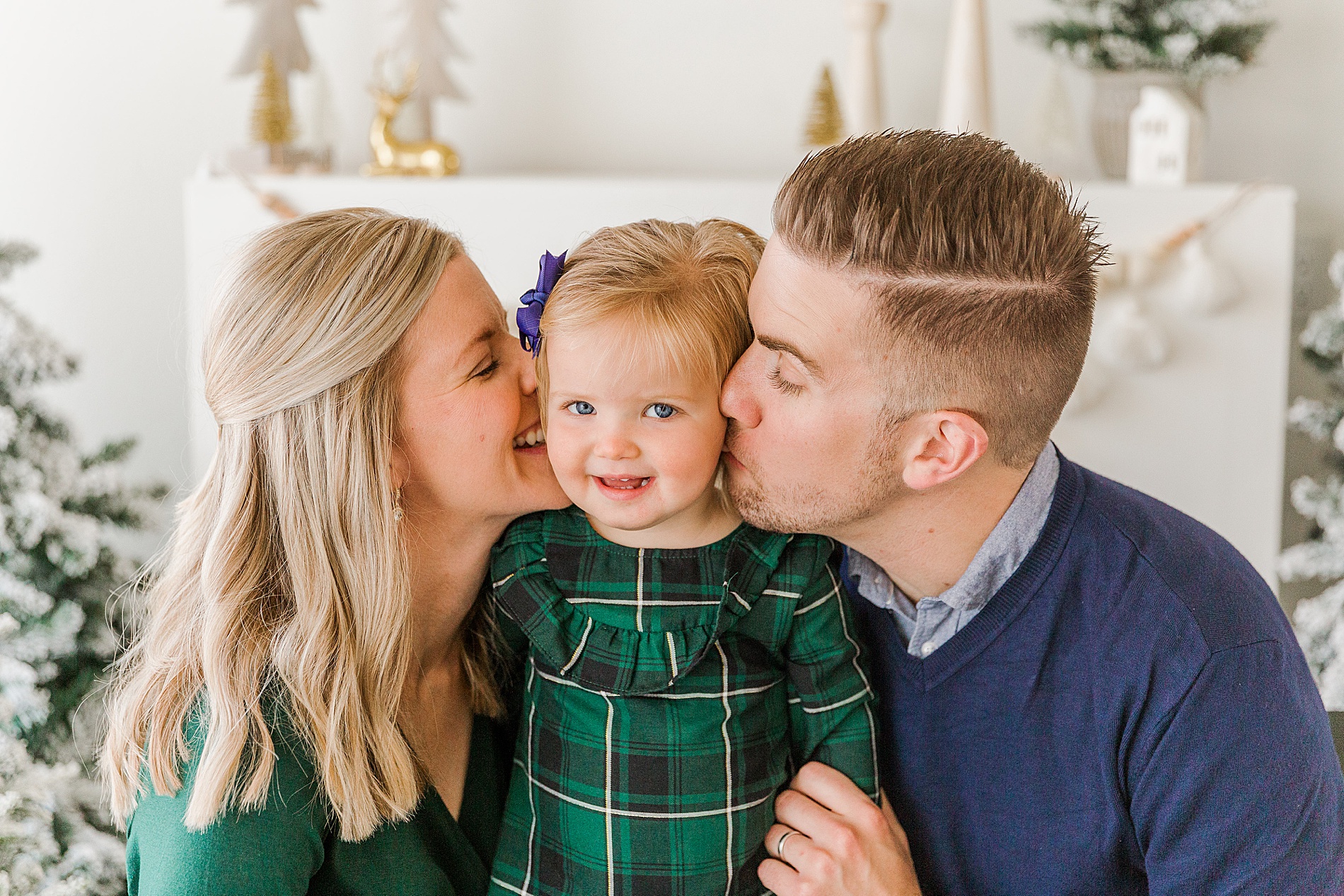 mom and dad kiss their daughter on the cheek during Sugarhill Studio Christmas Mini Sessions