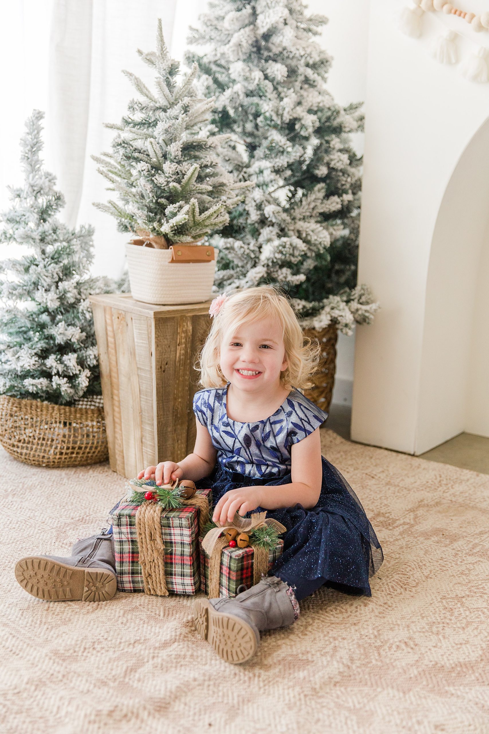little girl in holiday dress pretends to open presents during Colorado Christmas mini session