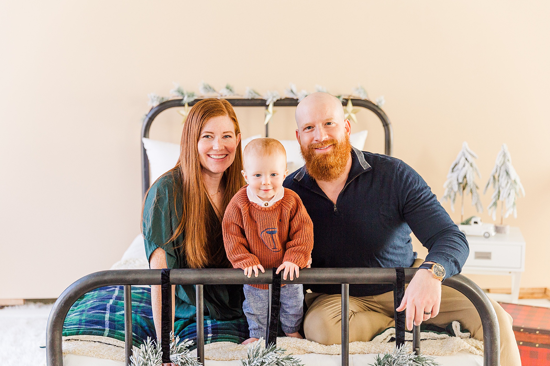 family of three sit on bed for holiday photos