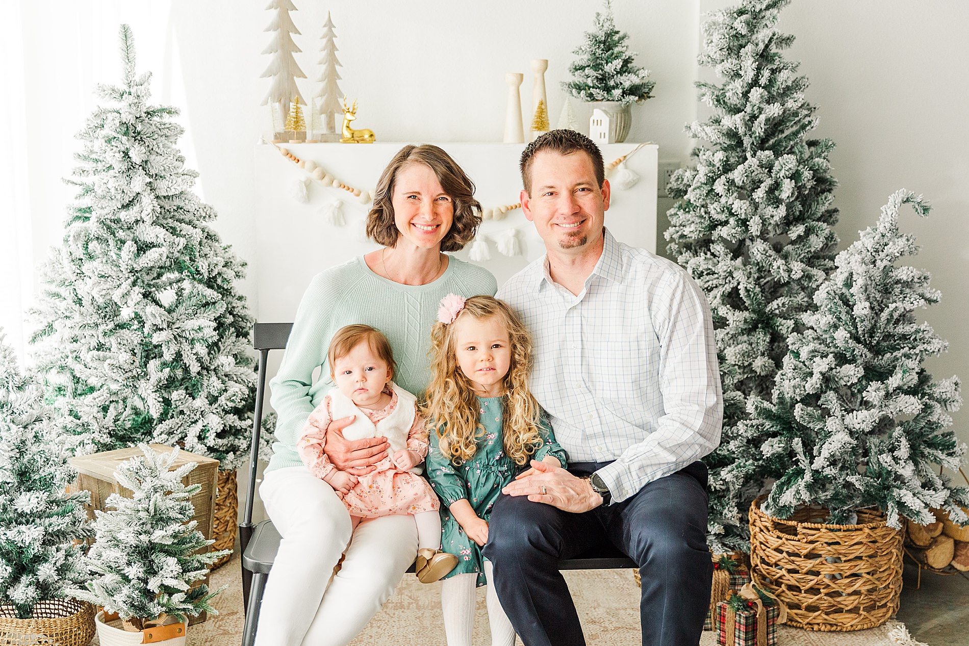 parents with two young girls sit together on a bench for a holiday mini session