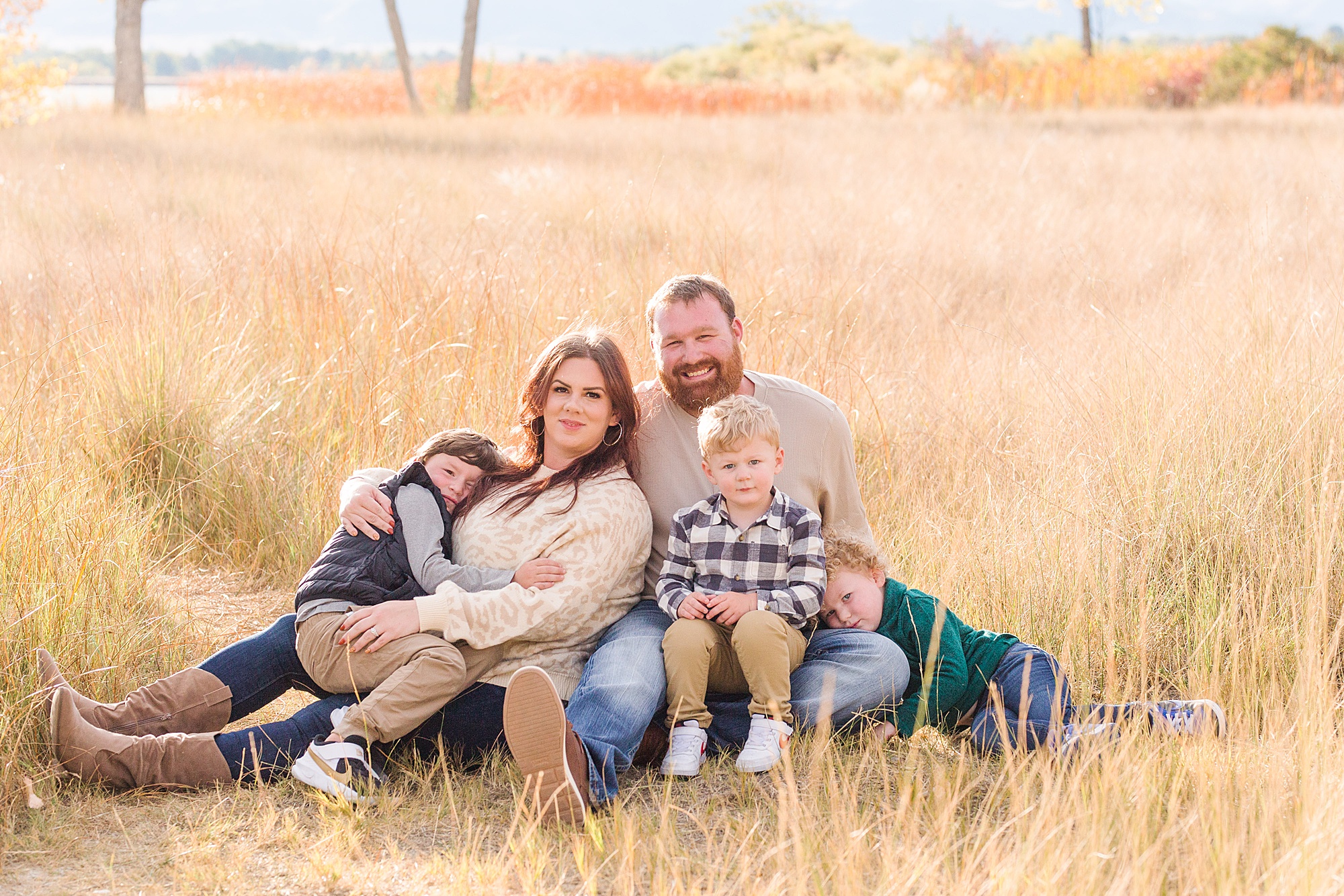family of five sits in tall grass during Fall Family Mini Sessions in Longmont Colorado