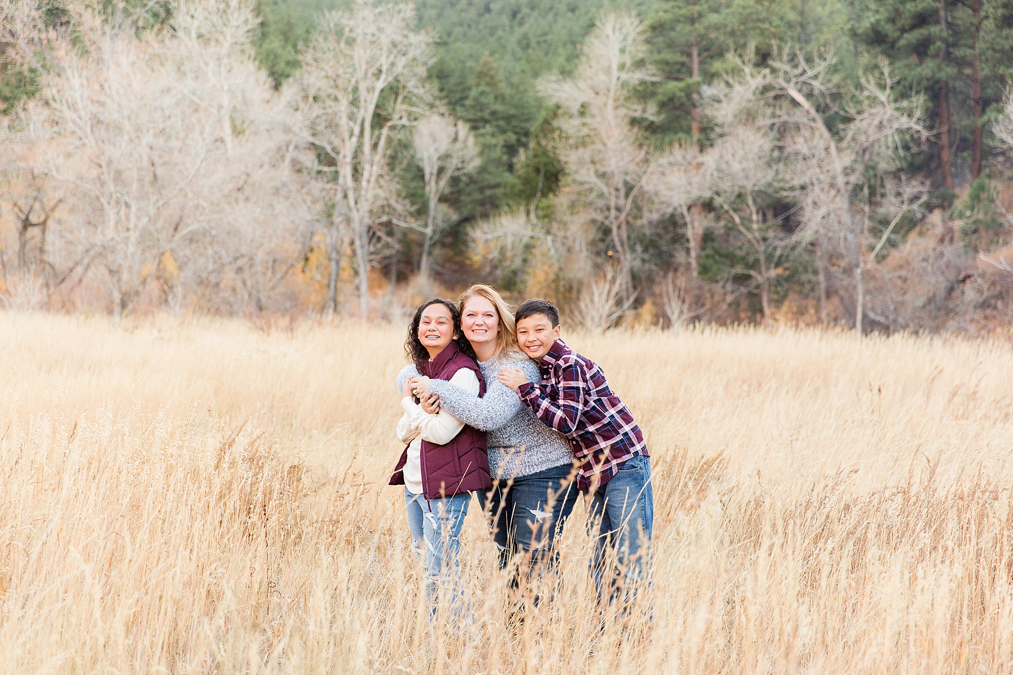 two teenagers hug their mom in the fields of Buckingham Park in Boulder, CO
