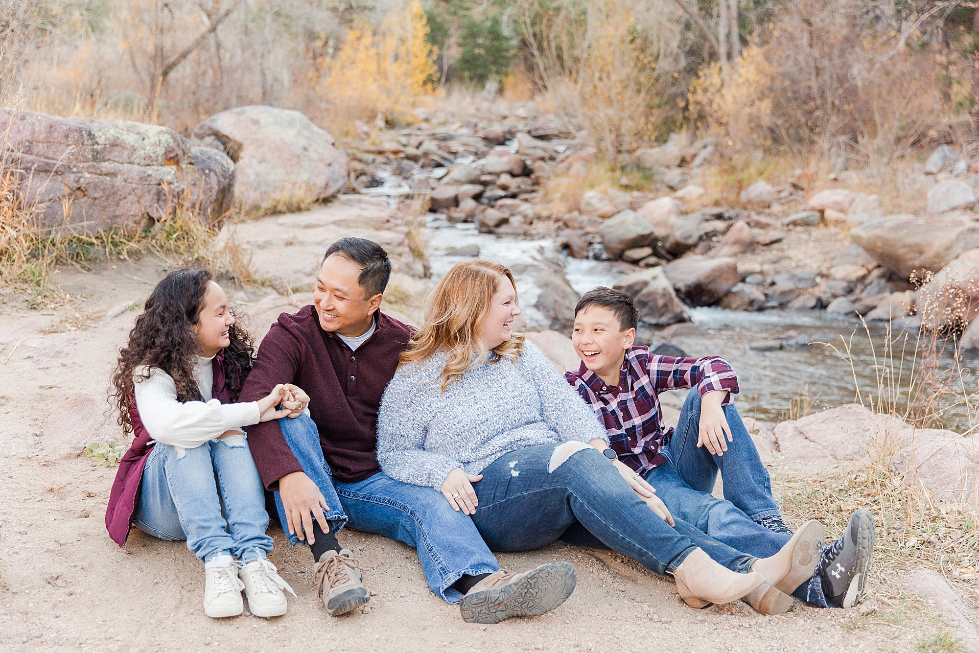 Family of four sit by rocky creek
