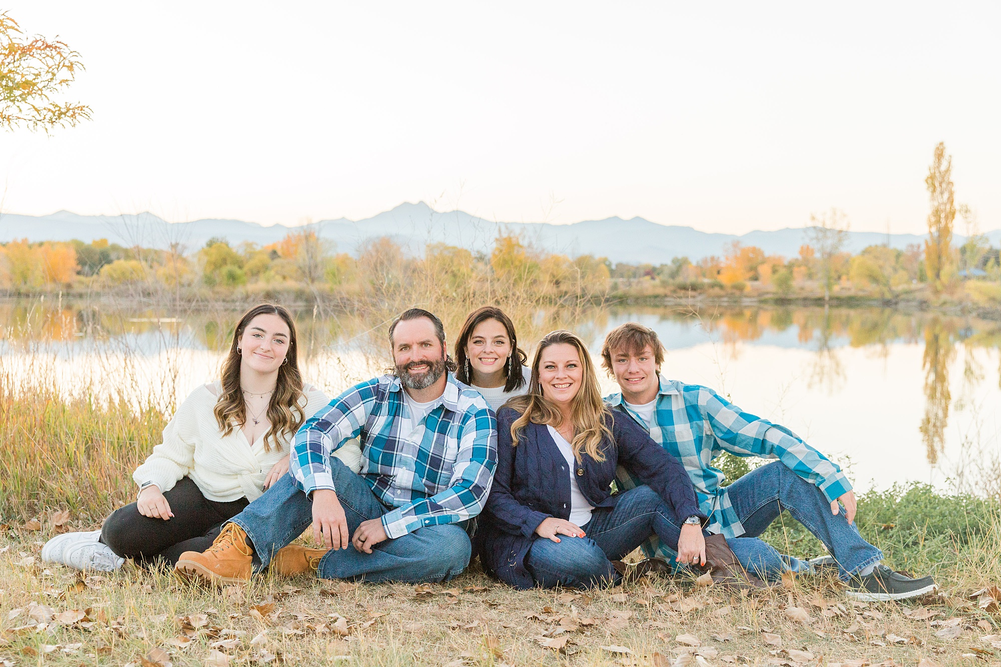 Family of five sits near lake with mountains in the background in Longmont CO