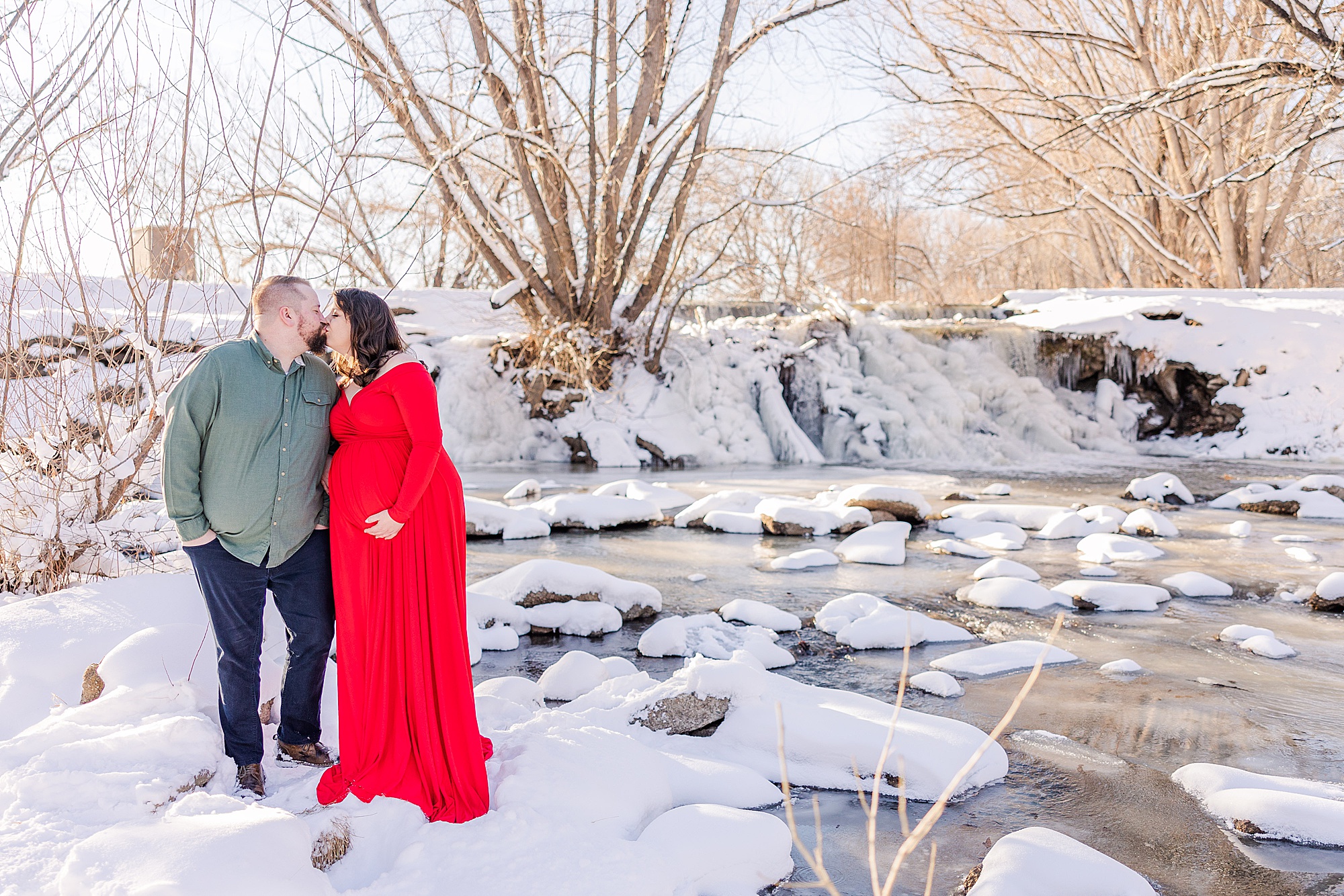 expectant couple kiss near snow covered pond in Longmont CO