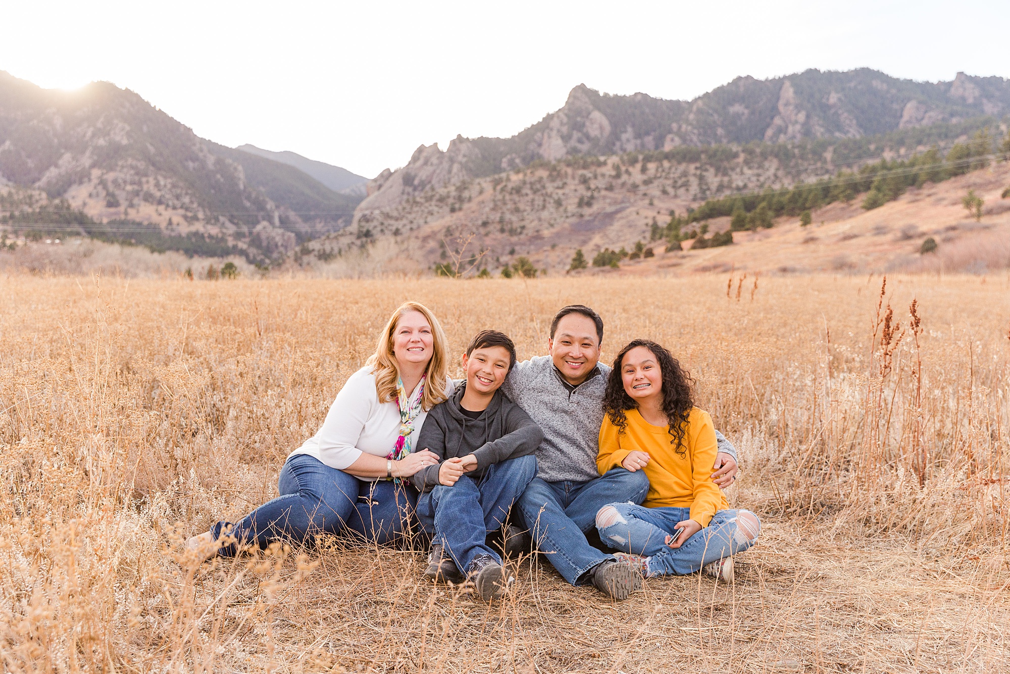 parents and two children sit in grass during South Mesa Trailhead Extended Family Session