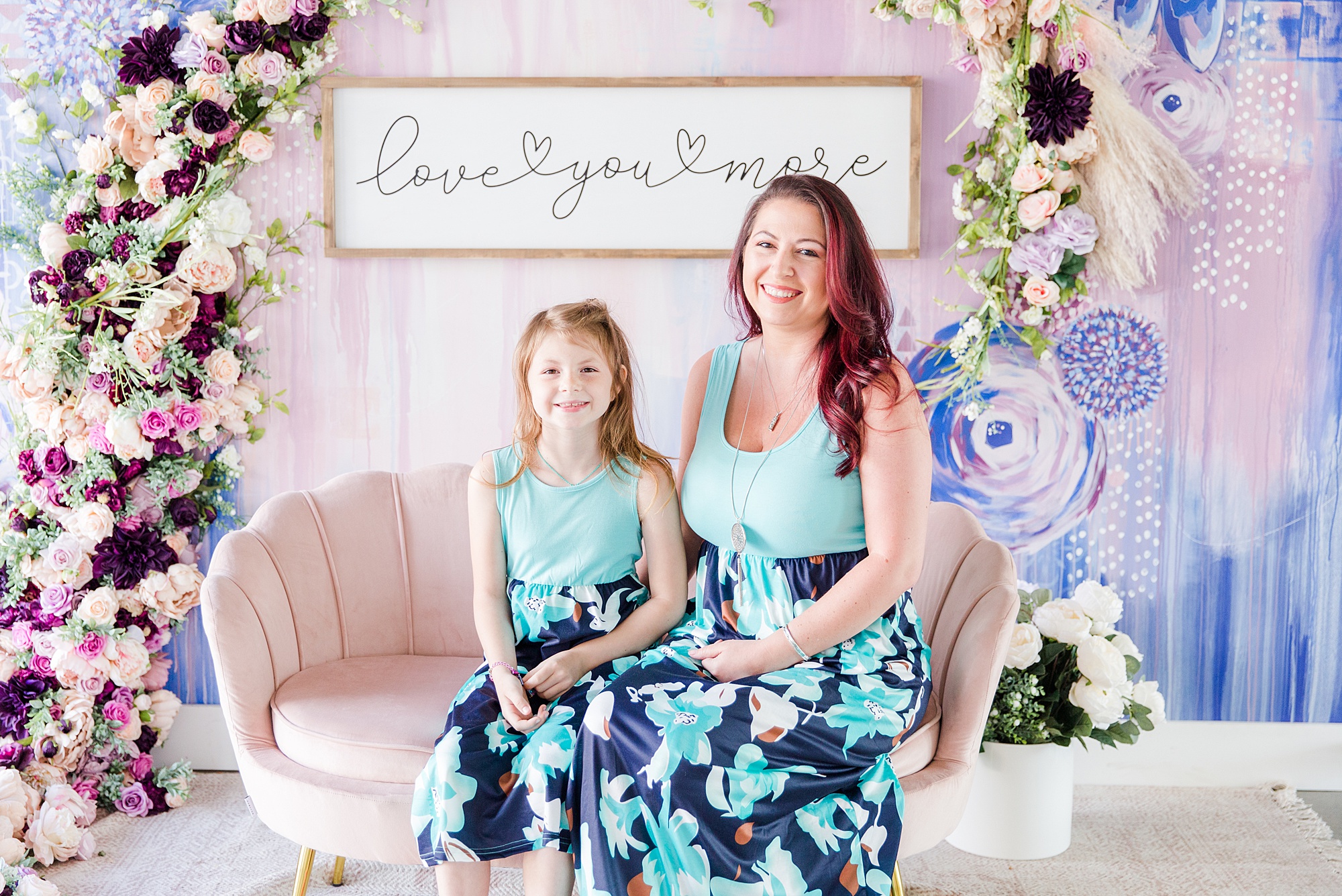 mom and daughter sit on pink couch during Mommy + Me Mini Sessions
