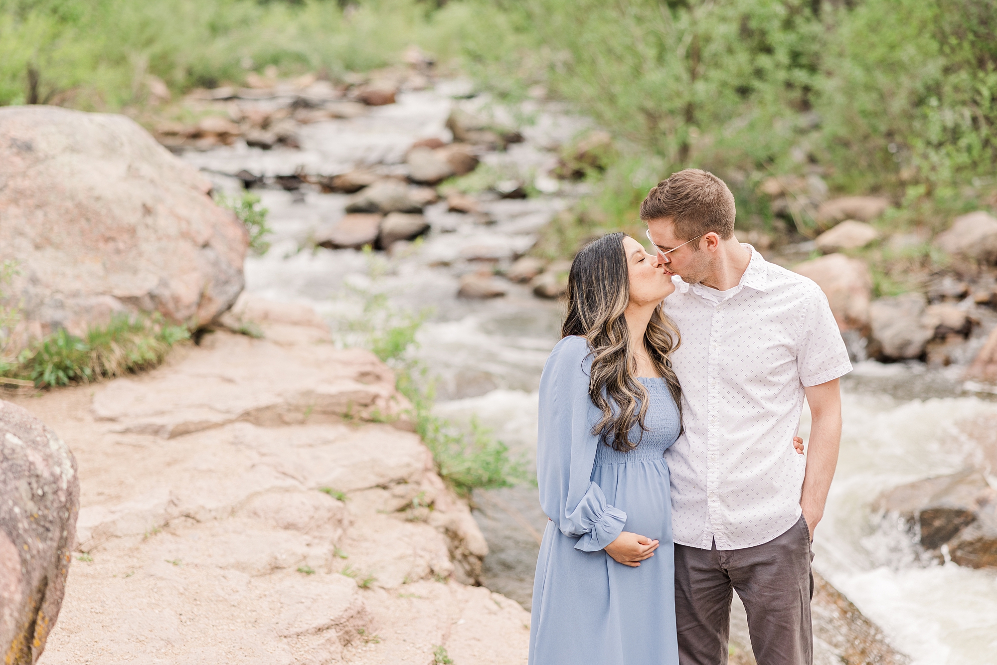 couple kiss by the creek at Buckingham Park in Boulder, CO by Colorado Maternity Photographer