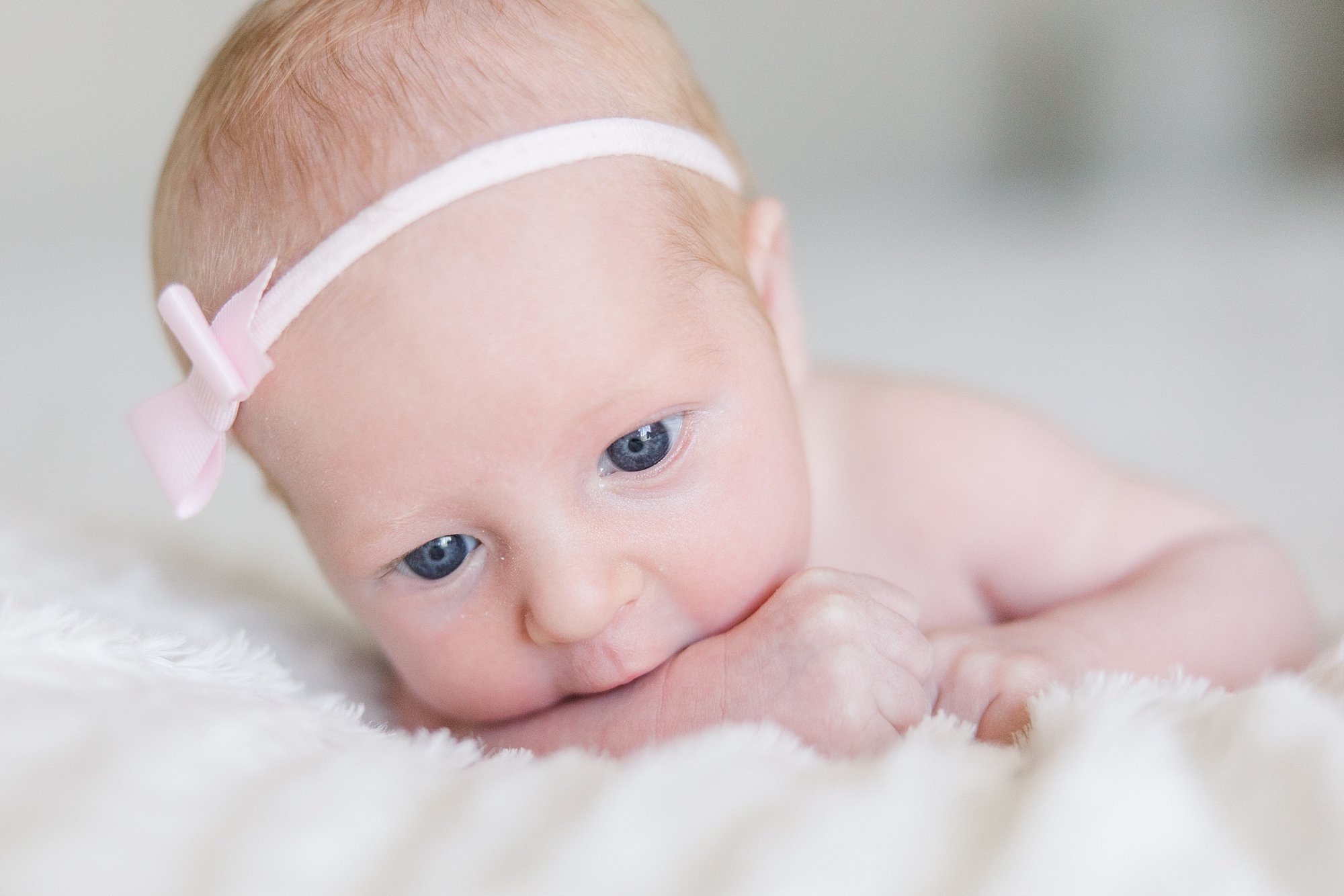 baby girl wearing a pink headband with blue eyes