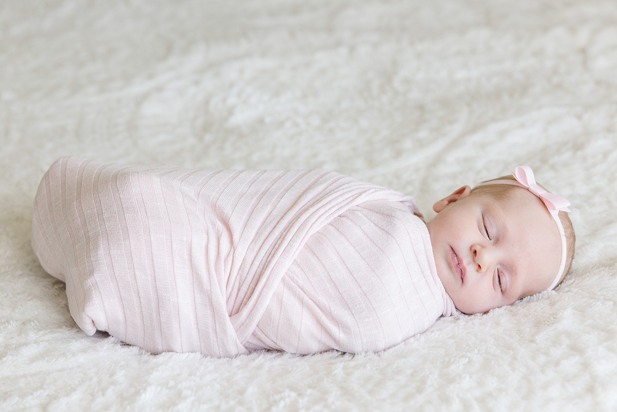 sleeping newborn girl wrapped in pink blanket
