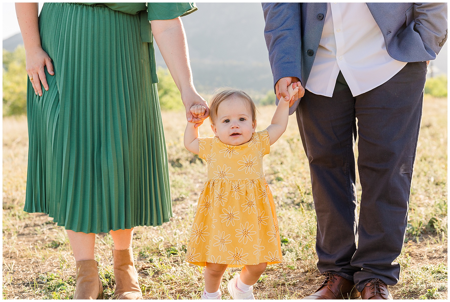 baby featured holding hands with mom and dad at mini session in Boulder 