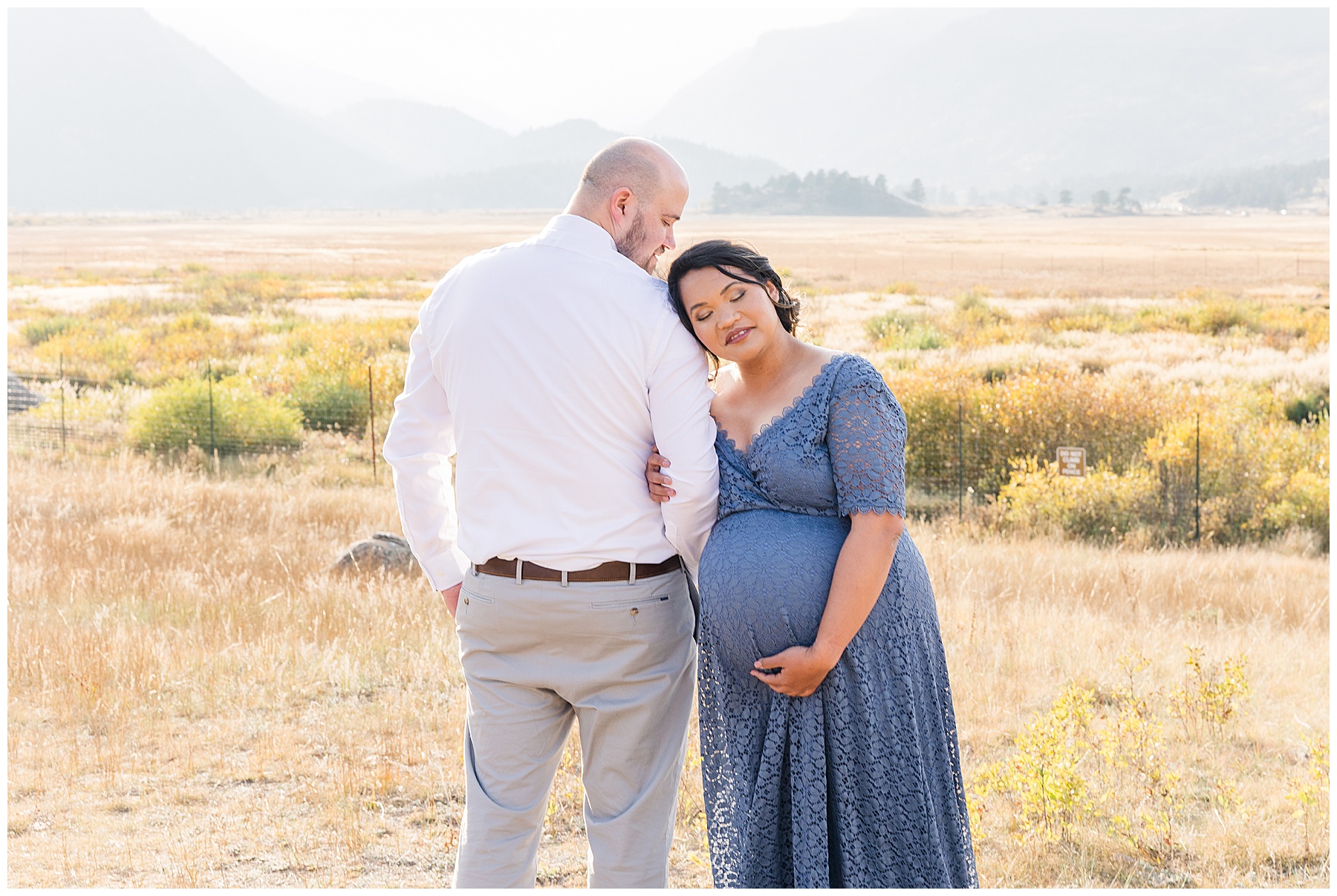 mom snuggling head on her husband while posing for maternity session with mountain background