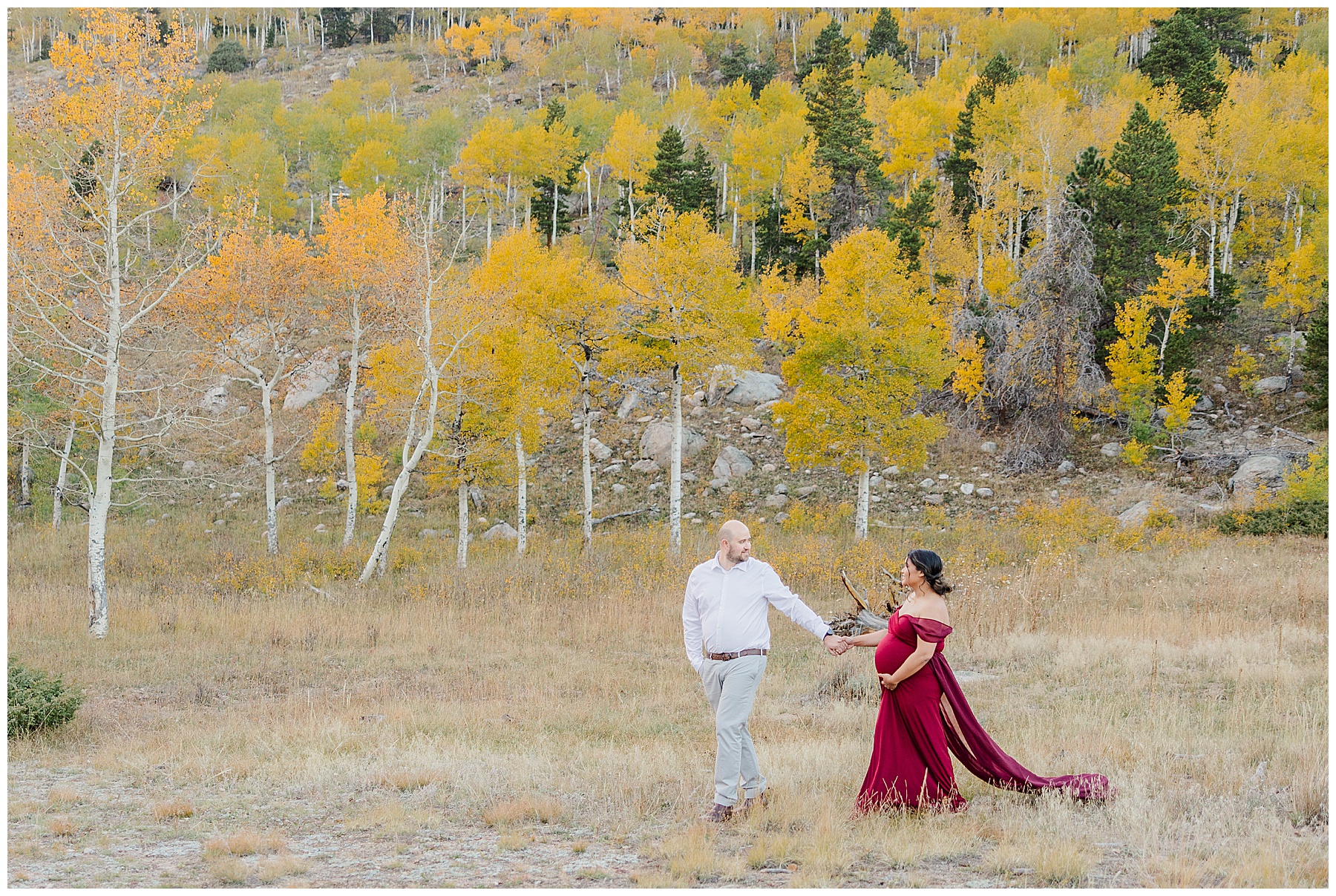 CO couple holding hands in front of yellow aspen trees