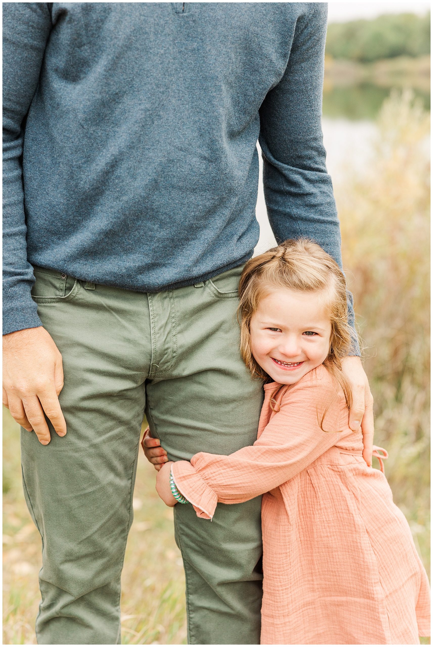 girl holds onto daddy's leg smiling 