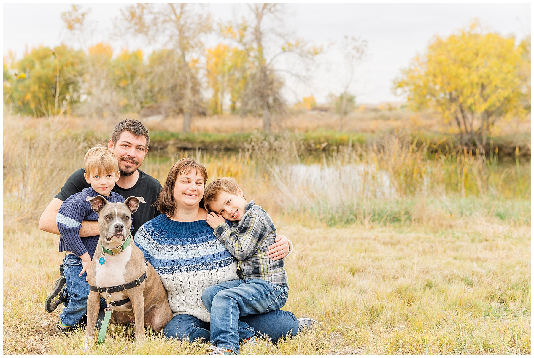 family of four sit on the ground to pose with their dog for Catherine Chamberlain Photography