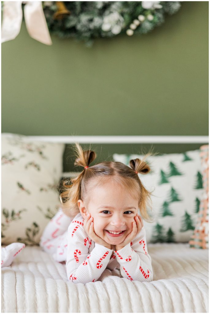 toddler girl with her hands on her cheeks in candy cane pajamas