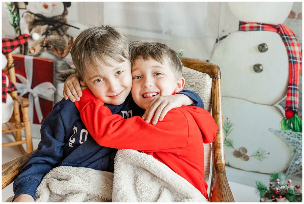 Twin boys snuggling on a chair with their arms wrapped around each other