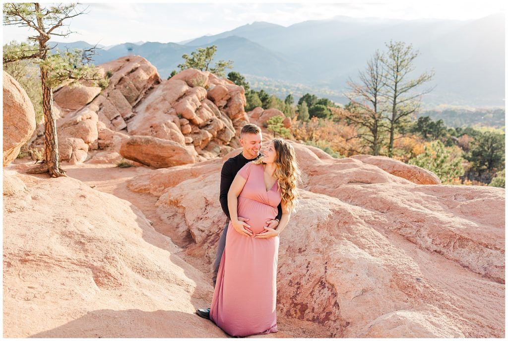 husband hugs pregnant wife from behind as she looks back at him during fall family mini session 