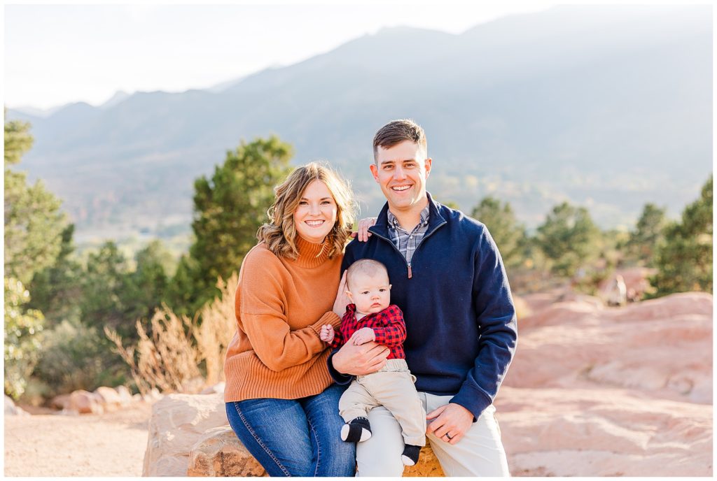 young Colorado family sit on a rock with Pikes Peak in the background of fall family mini sessions