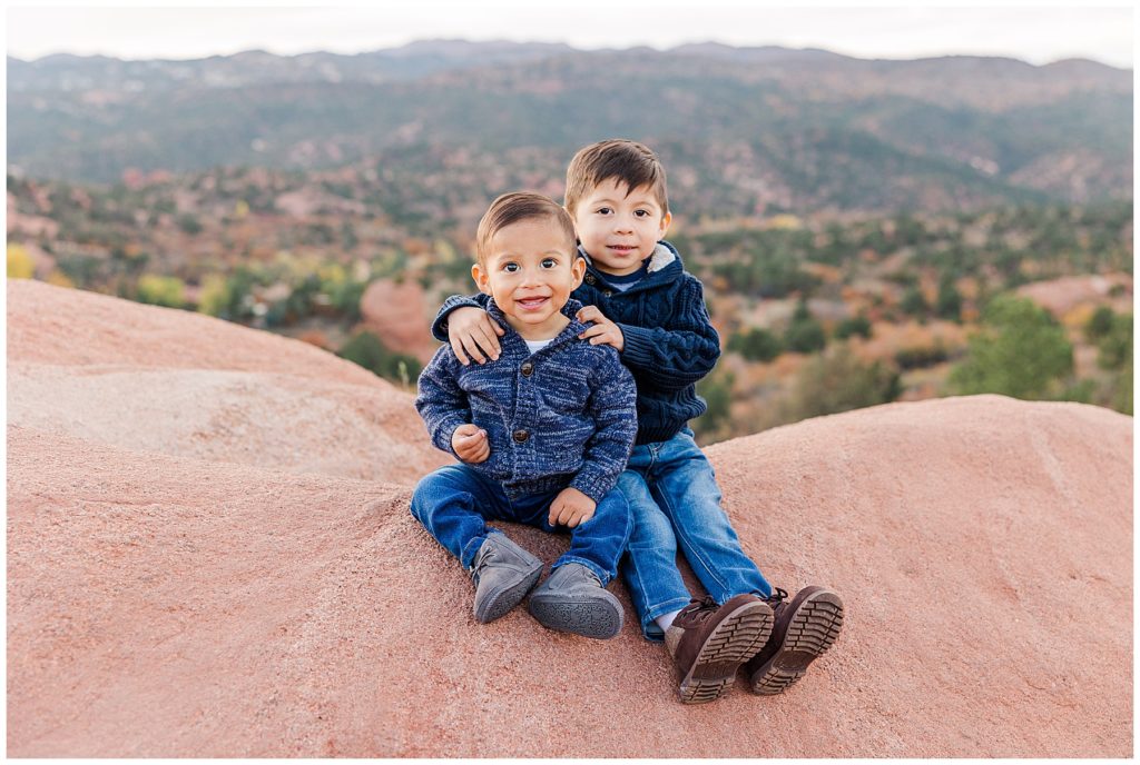 two young brothers sit together at Garden of the Gods in Colorado Springs, CO