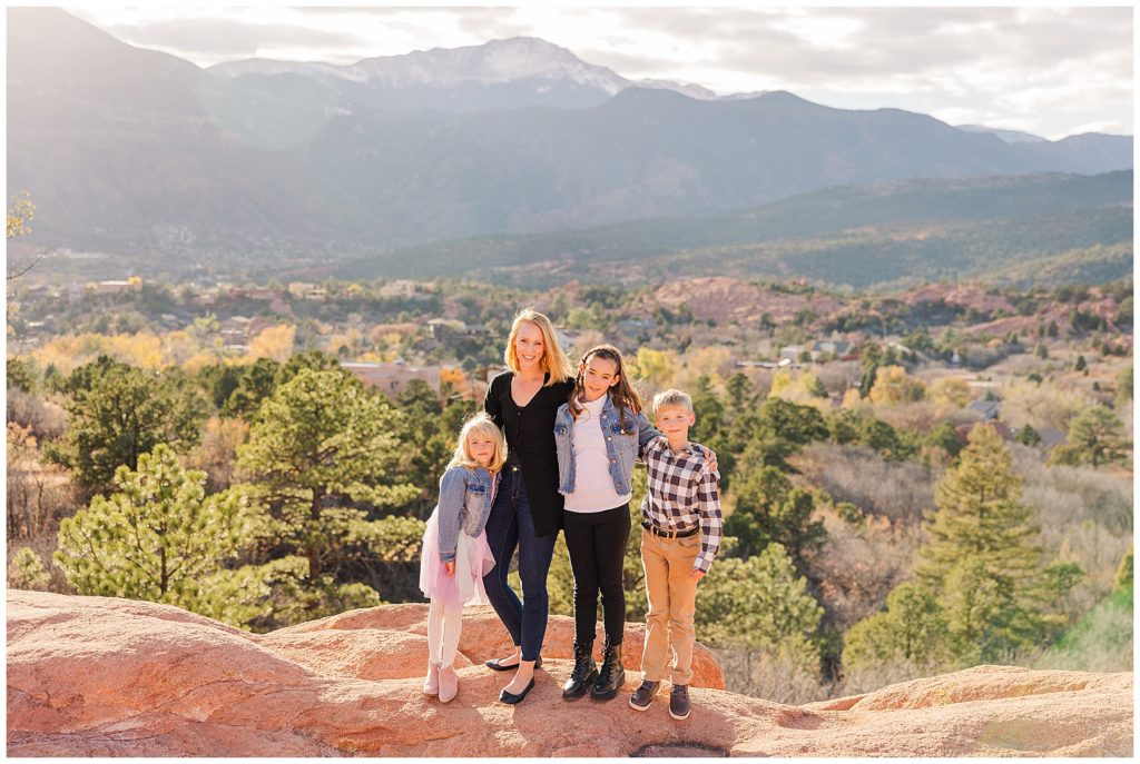 mother poses with her three kids with a valley and mountain behind them at Garden of the Gods