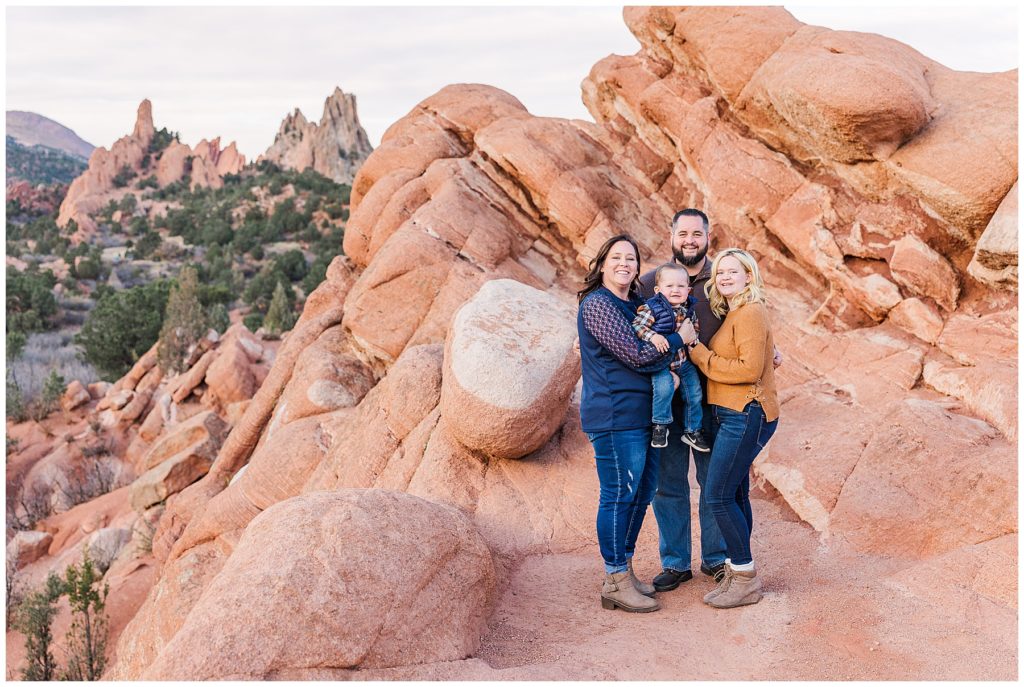 mother father son and daughter stand on a huge sandstone rock formation in Garden of the Gods