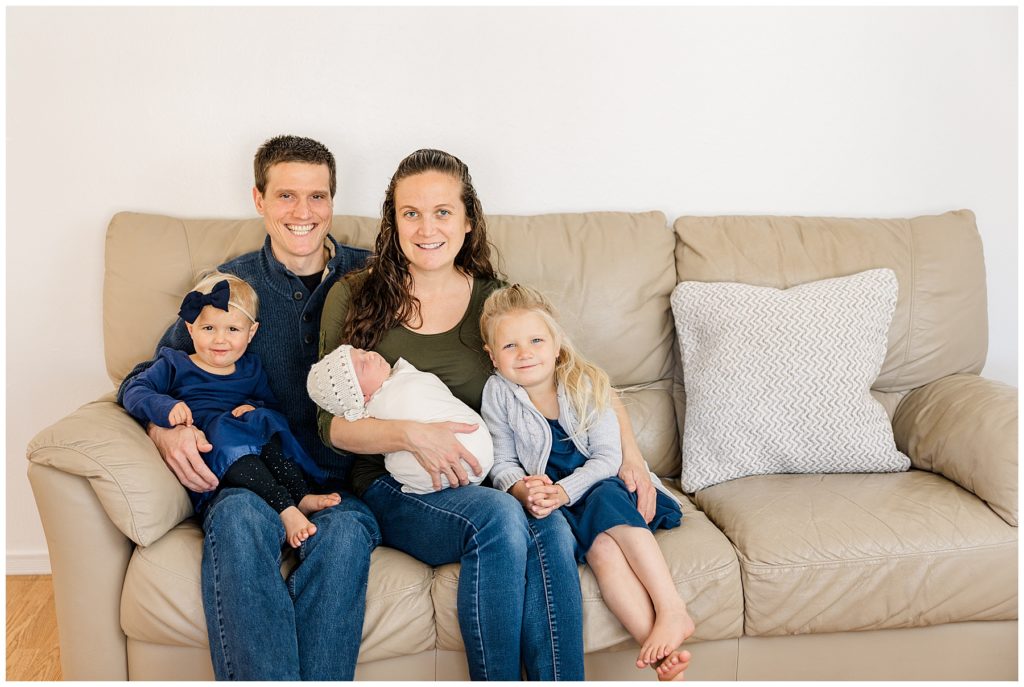 family of five pose on the couch for in-home Colorado newborn session
