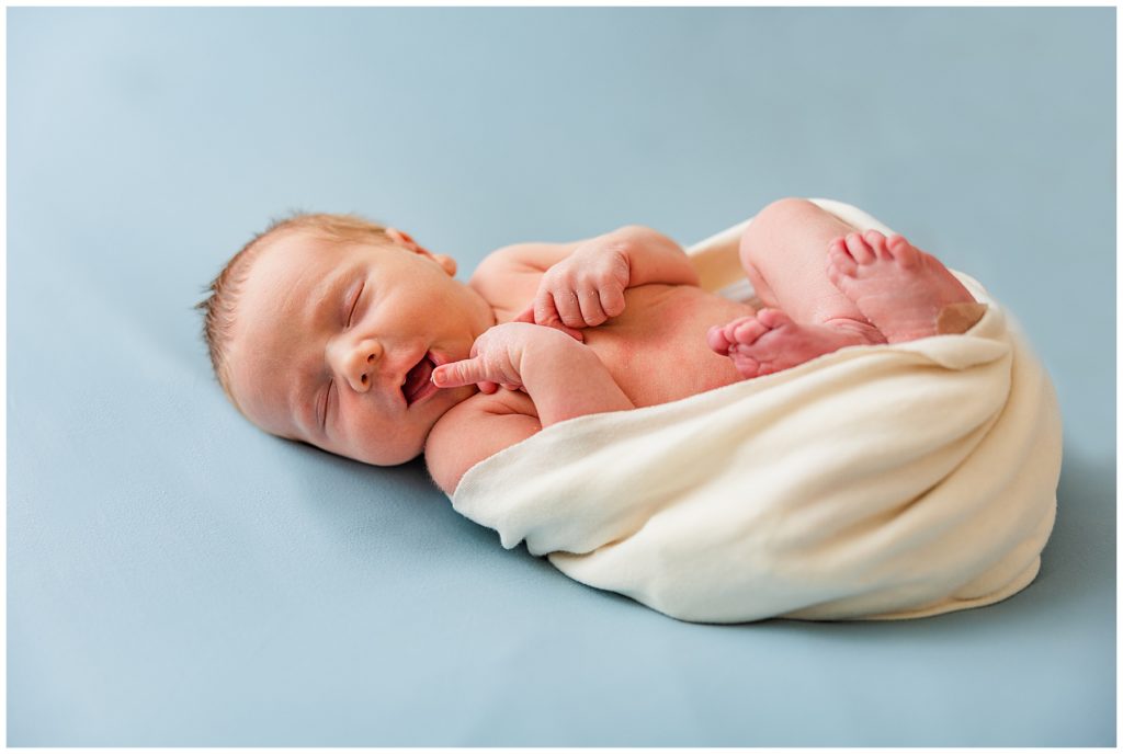 newborn lays with open swaddle for in-home photography session in Northern Colorado