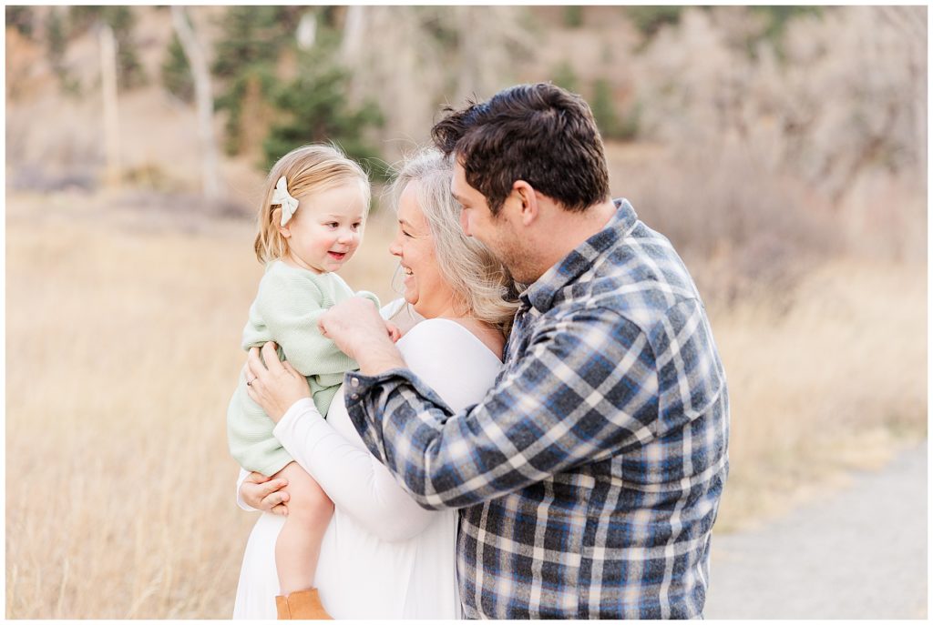 mom and dad face their little girl during maternity session