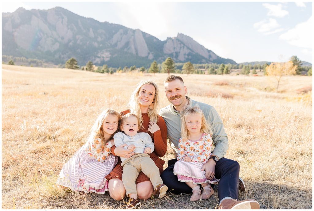 Family of five sit on the ground in front of Boulder flatirons for Catherine Chamberlain Photography mini sessions