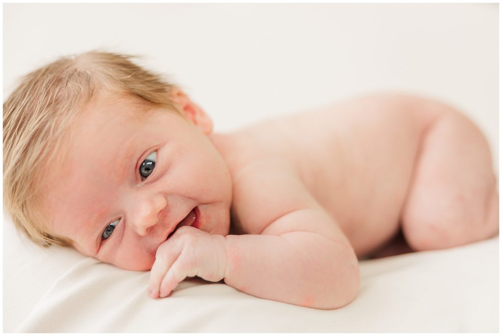 Infant sucks on her hands during an indoor newborn photo session