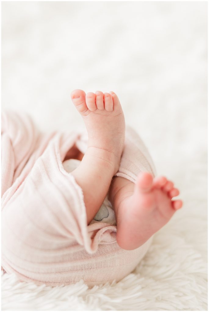 Close up shot of the newborn's tiny feet sticking out of the swaddle during family session of newborn photos