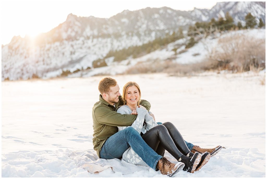 Boyfriend looks at his girlfriend while seated on the snow during photography session in Boulder CO