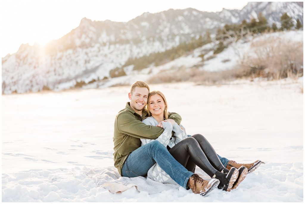 Couple sits together with their legs out in the snow for a Colorado photo shoot  