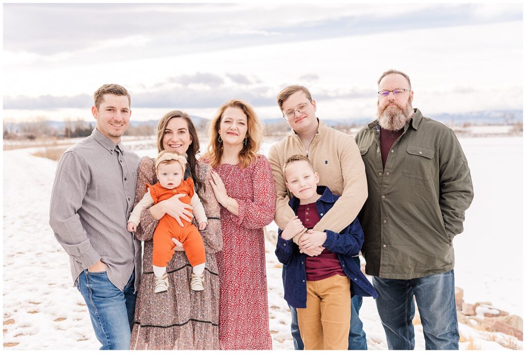 Extended family snuggle together as they stand in front of mountains for a winter family session