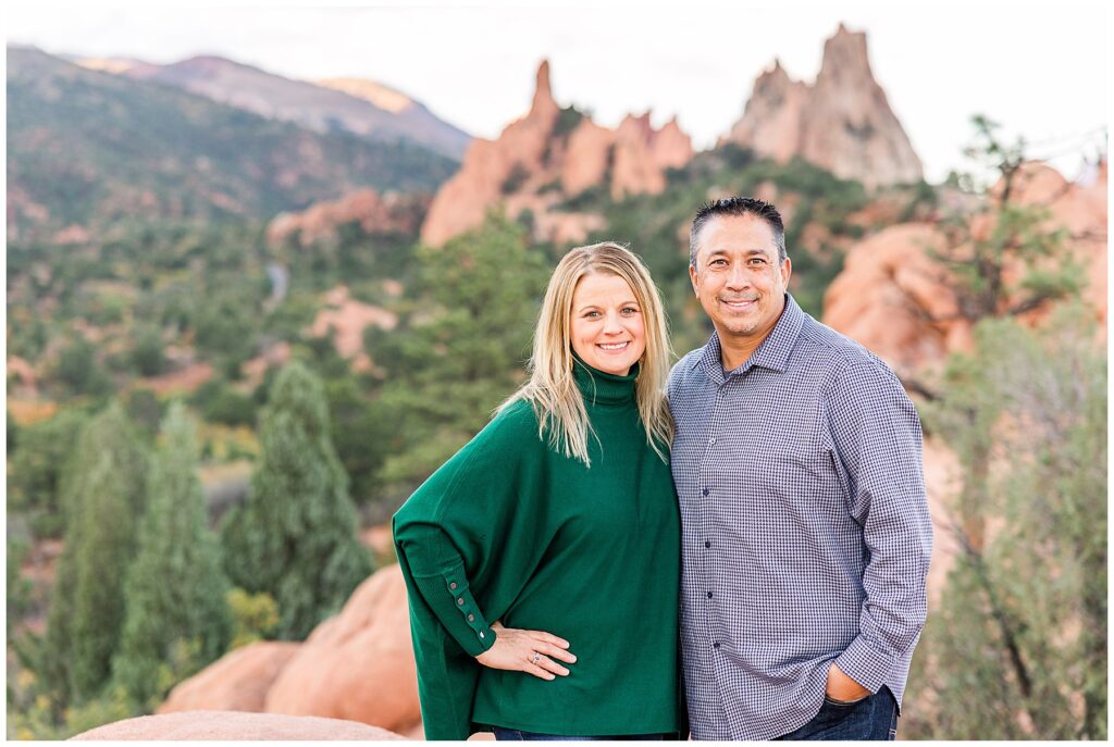 Couple stands and poses together as wife puts her hand on her hip and husband has his hand in his pocket during Colorado Springs Family Session