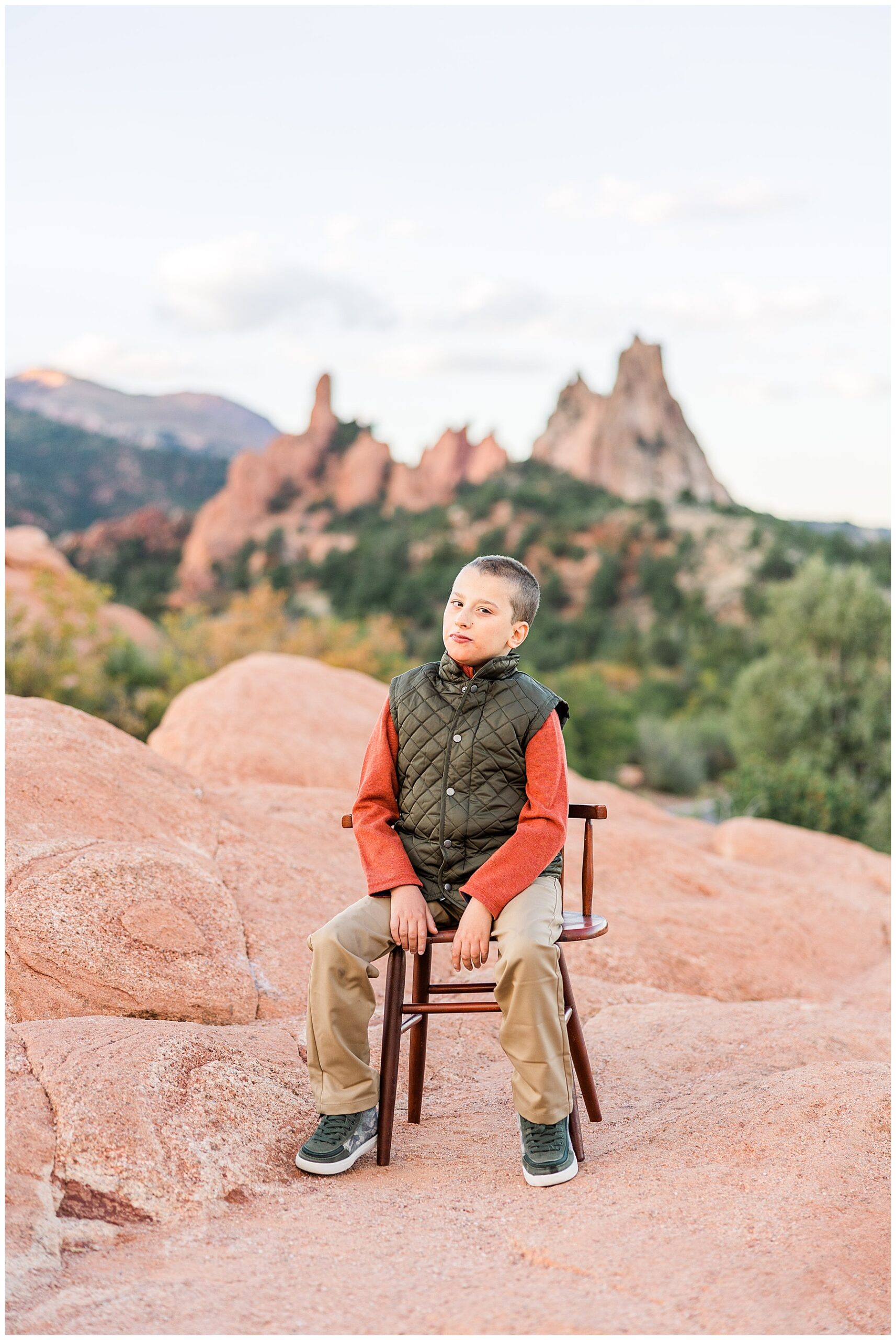 Boy sits and poses on a chair with rock formations in the background during a Colorado Springs Family Session