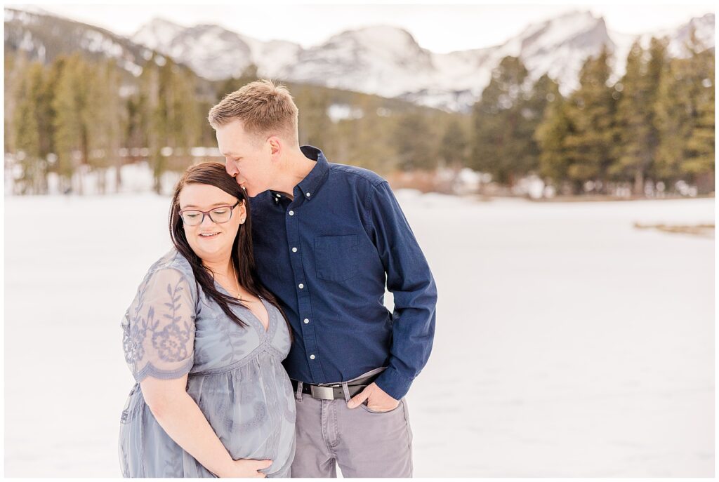 Husband tenderly kisses his wife's forehead during this Sprague Lake maternity shoot