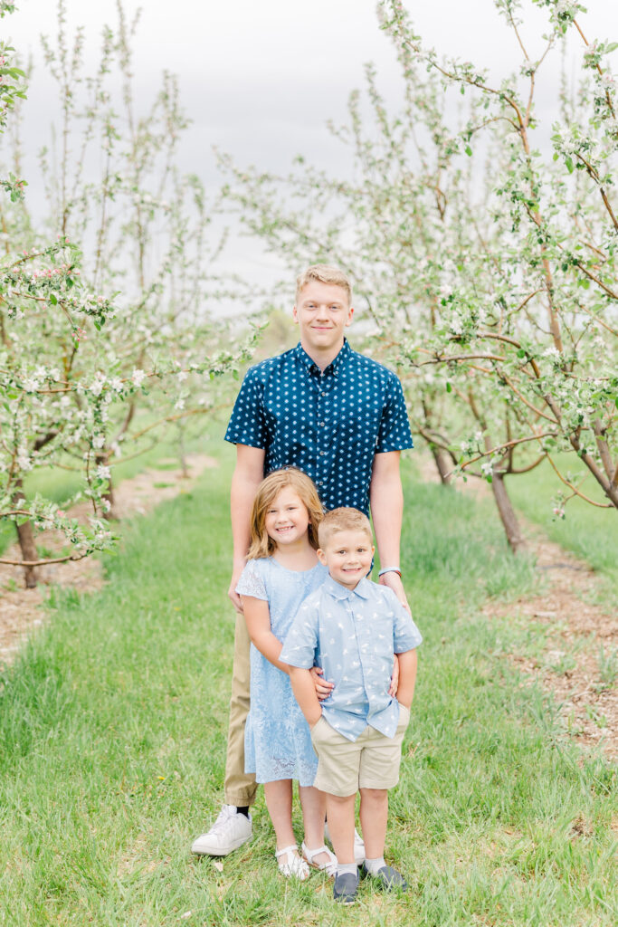 Niece and nephew stand with their uncle during Lantzy Extended Family Session at Ya Ya Orchard in Longmont, CO