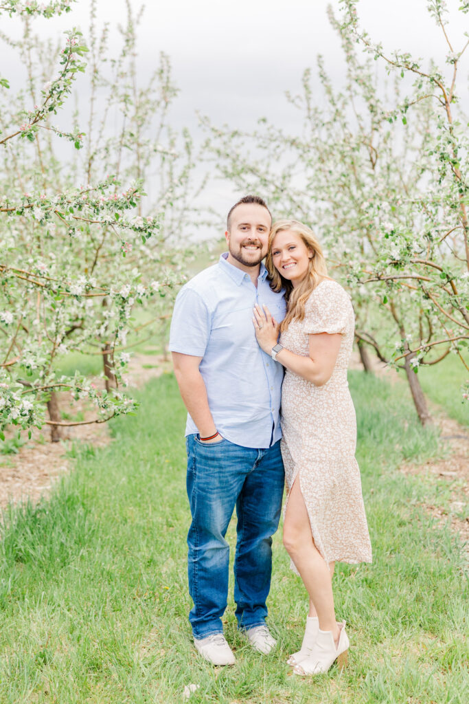 Couple pose together in blossoming trees during Lantzy Extended Family Session at Ya Ya Orchard in Longmont, CO