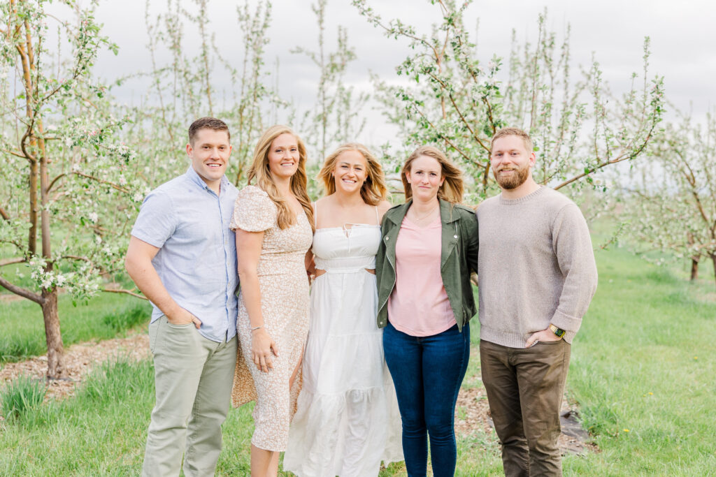 Five siblings stand together in a beautiful orchard in Longmont, CO