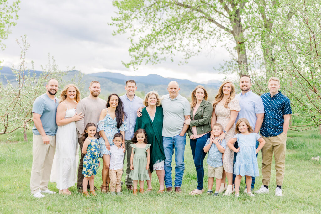 Extended family stand and pose together with a mountainous background at Ya Ya Orchard in Longmont, CO