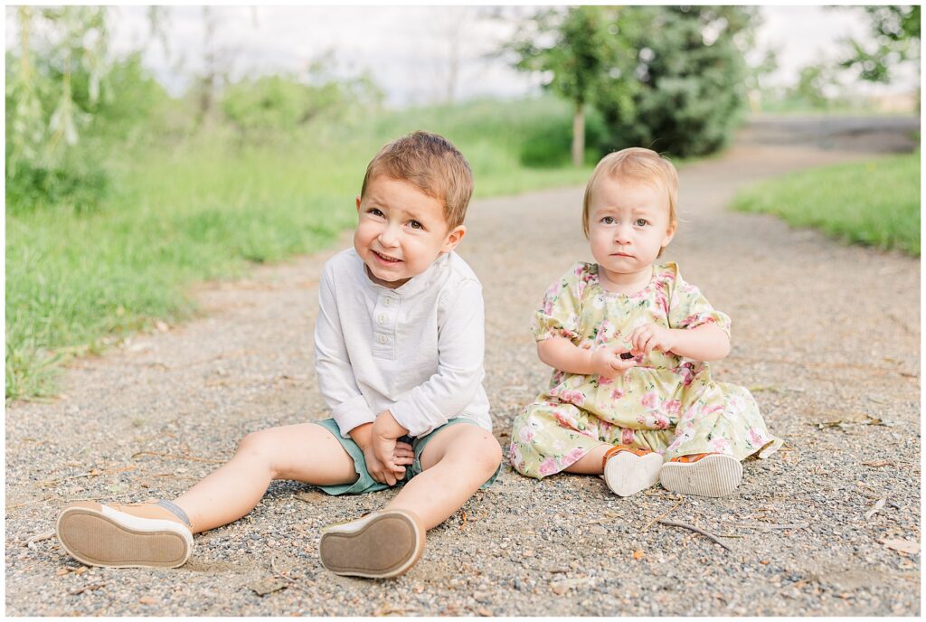 Two young siblings sit on the ground during South Denver Mini Sessions