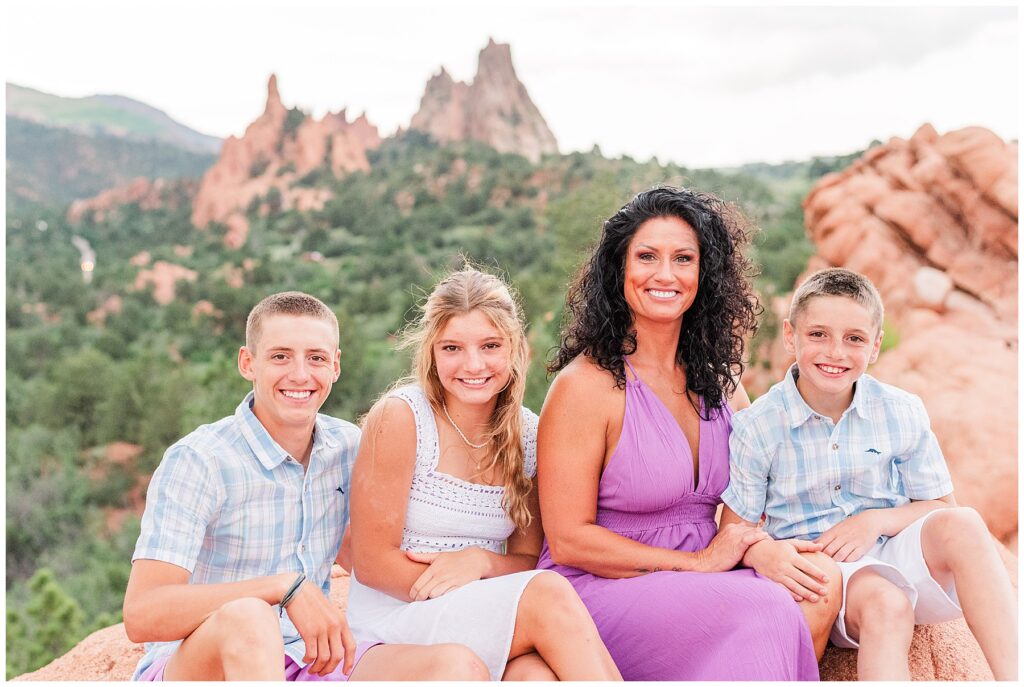 Mom and her three kids sit and pose for Colorado Springs family photos at Garden of the Gods