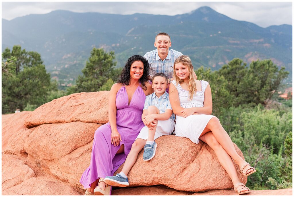 Mother and her three kids pose on a rock formation for Colorado Springs family photos at Garden of the Gods