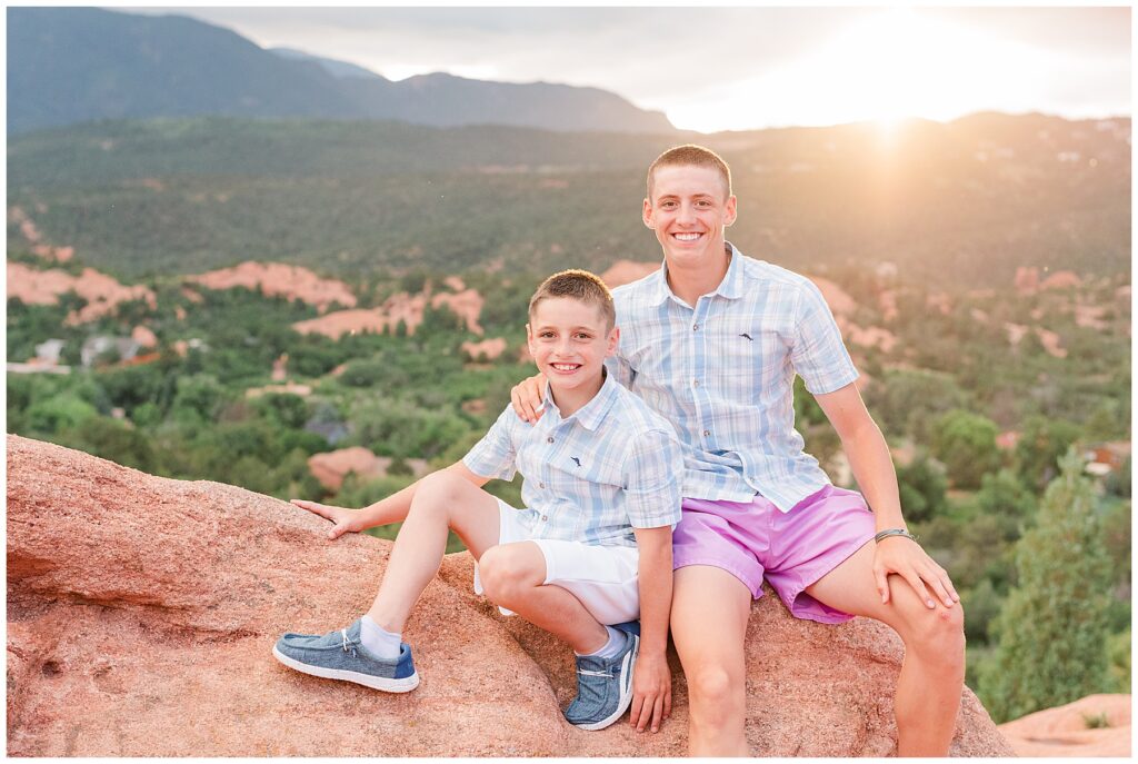 Brothers sit on a red rock for Colorado Springs family photos at Garden of the Gods